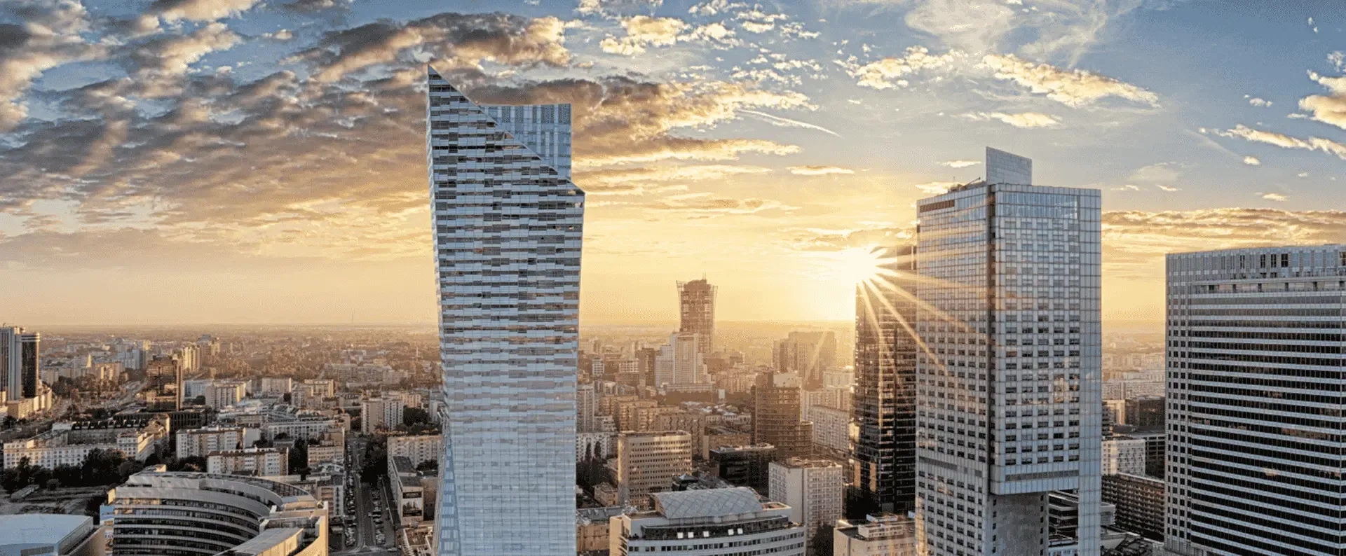 Drapacze chmur wznoszą się wyraźnie na tle żywego, zachodzącego słońca.