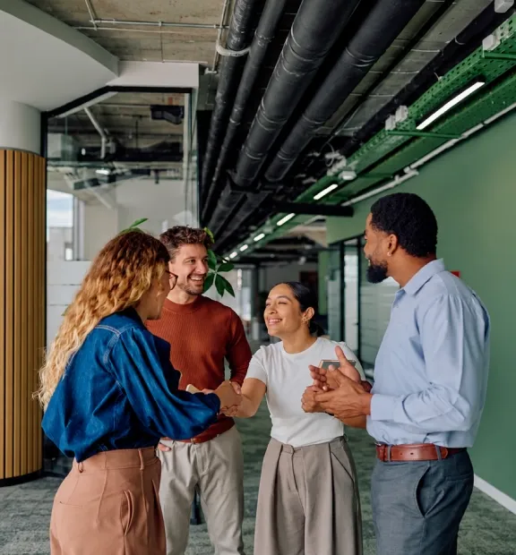 Colleagues greeting each other in a vibrant office with green walls.