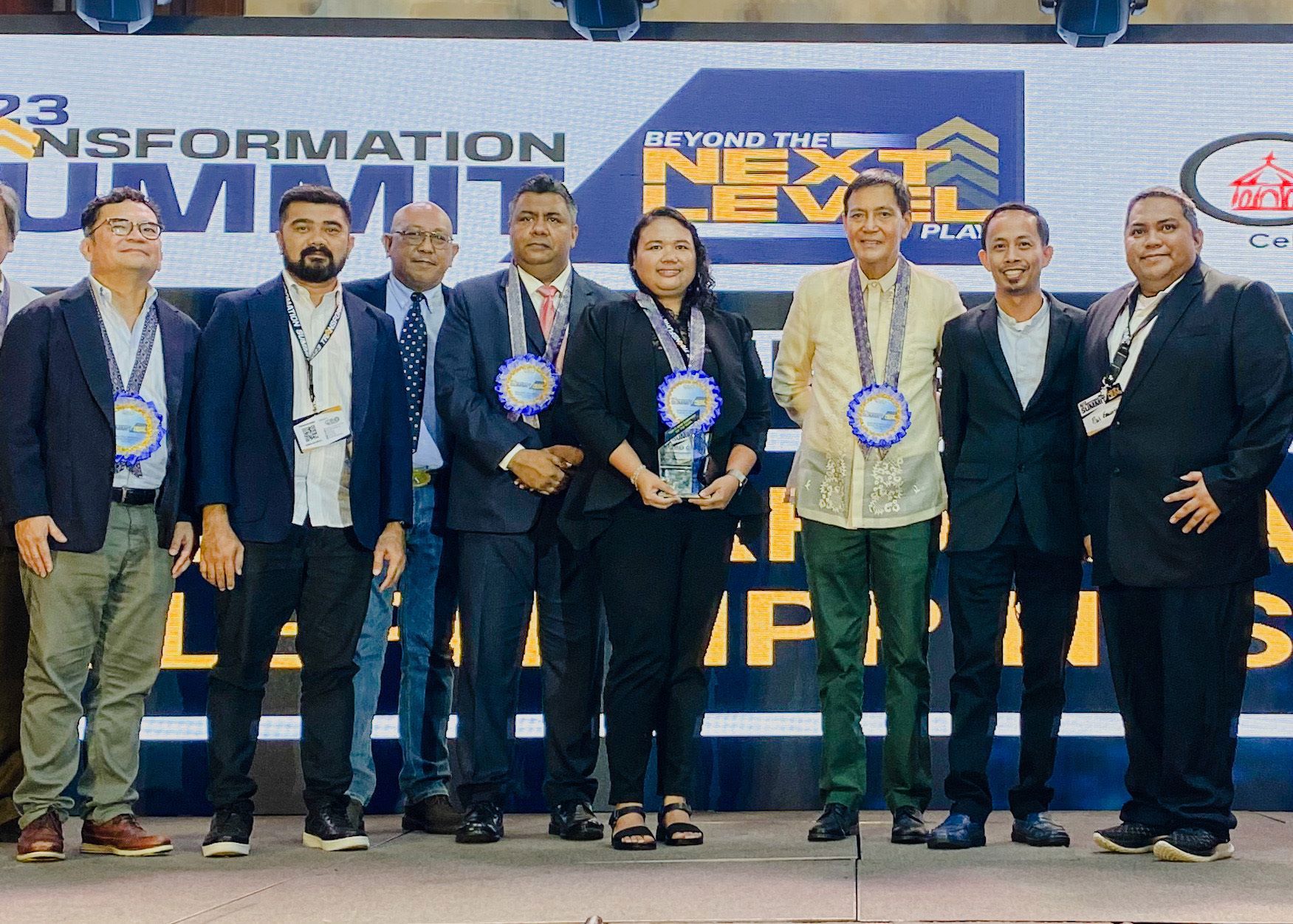 Group of professionals on stage with awards and medallions at the Transformation Summit 2023.