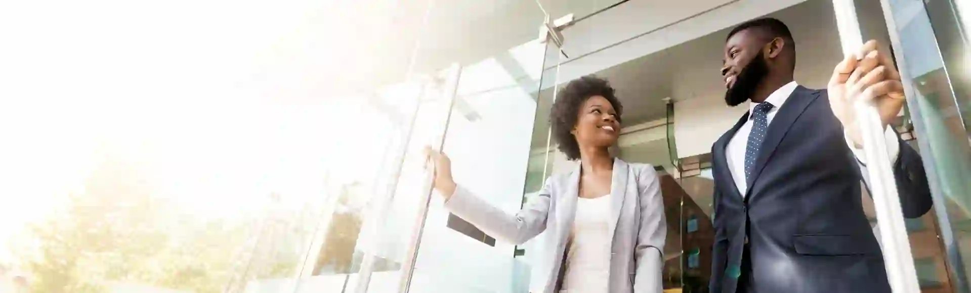 African business couple opening a bright glass door, symbolizing the start of new business opportunities, challenges, and paths to success.