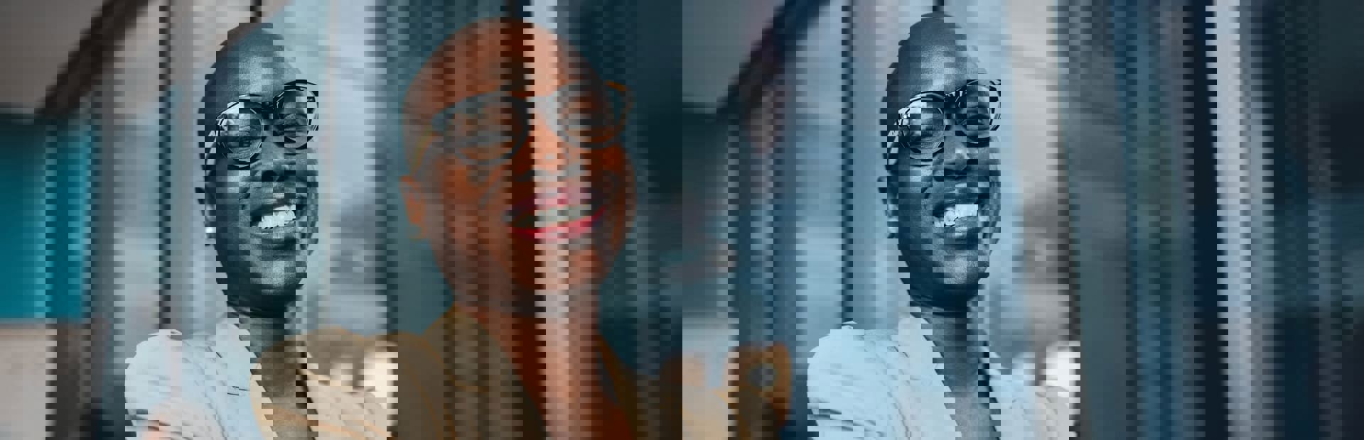  Smiling African businesswoman in elegant attire and glasses, working in a modern office with large glass windows.