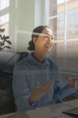 Smiling professional woman speaking during a video meeting in a bright office.