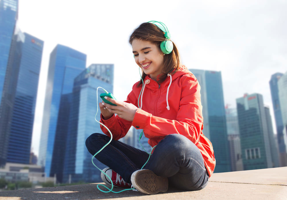 Woman listening to music sitting cross-legged outdoors