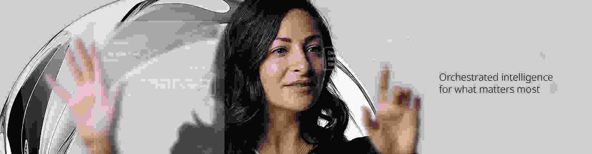 Woman interacting with transparent digital interface displaying AI-generated customer support suggestions, with the text 'Orchestrated intelligence for what matters the most' in the background.
