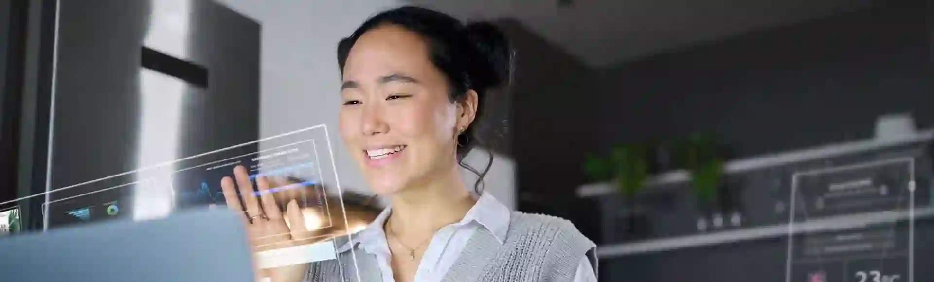 Asian woman working on a computer, interacting with futuristic 3D elements emerging from the screen, representing Human CX innovation.