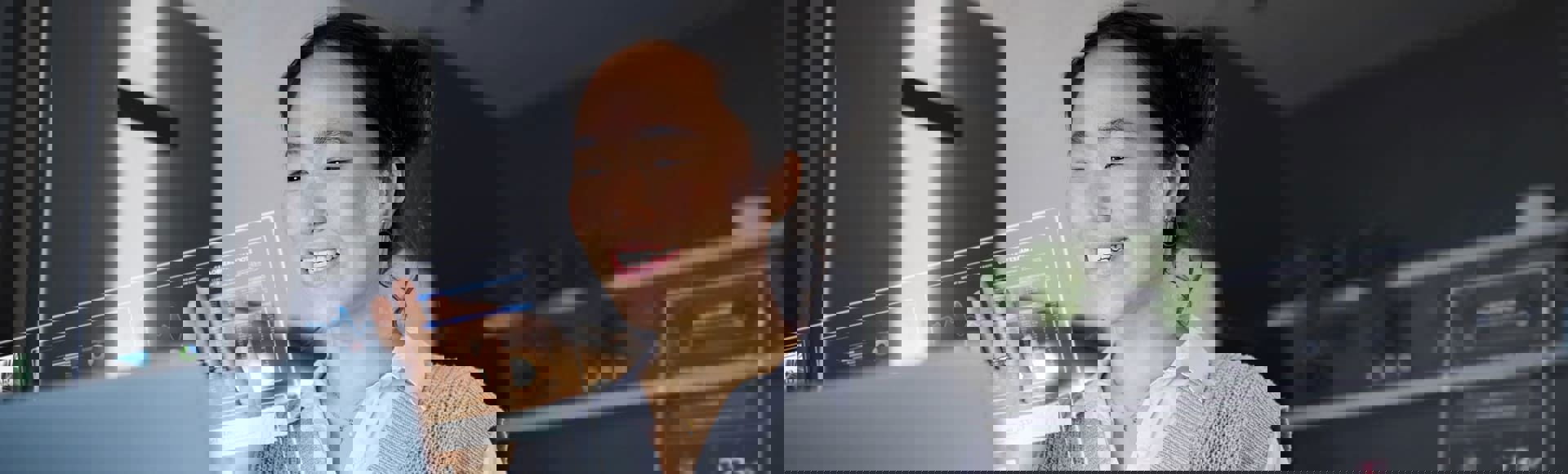 Asian woman working on a computer, interacting with futuristic 3D elements emerging from the screen, representing Human CX innovation.