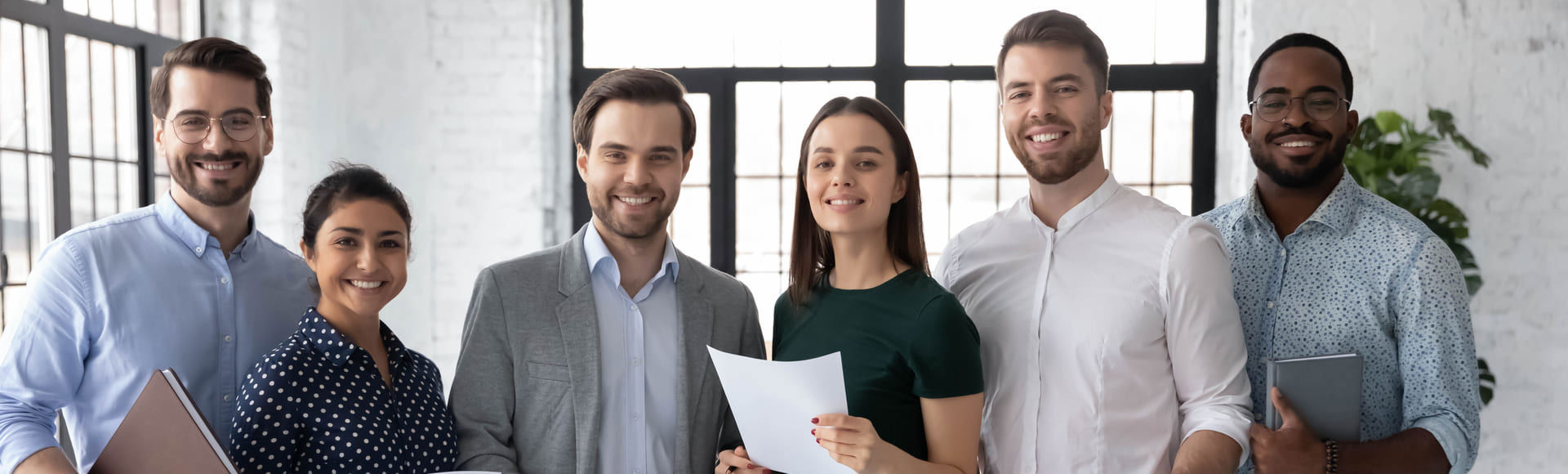Group of diverse employees in a modern, well-lit office celebrating a team achievement with smiles and friendly gestures.