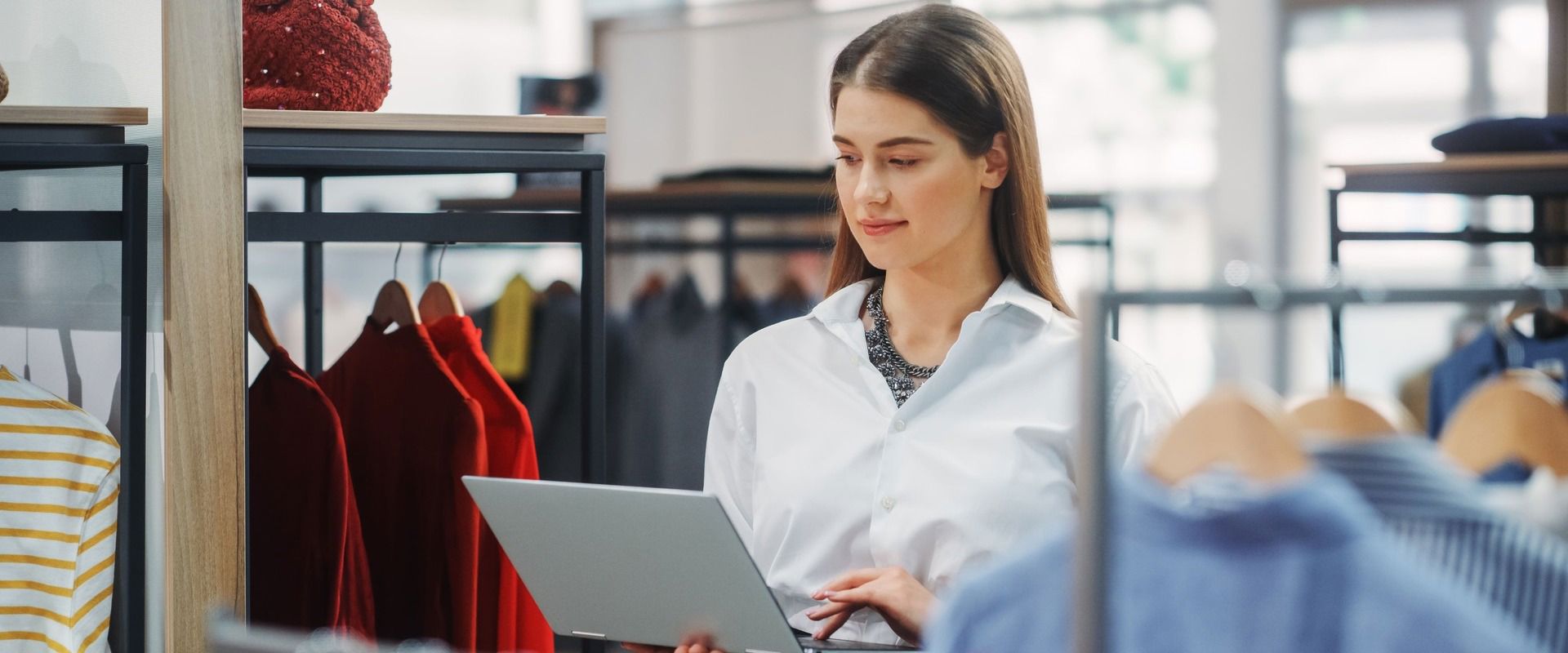 Woman using her laptop inside a clothing store, illustrating PR on shoppers willing to pay more for good customer experience.