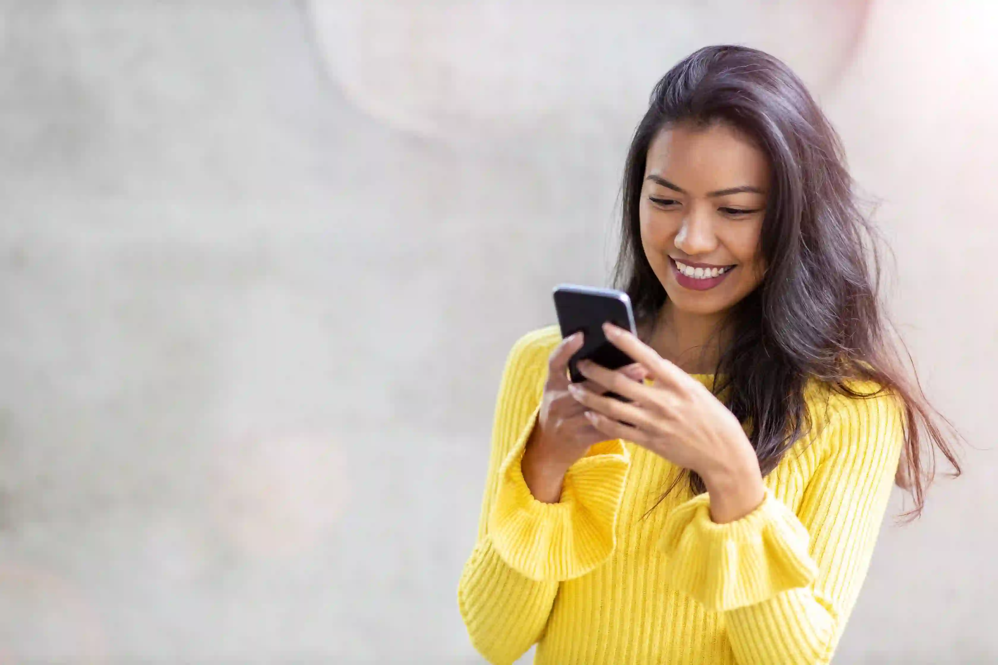Young smiling asian girl browshing her cellphone