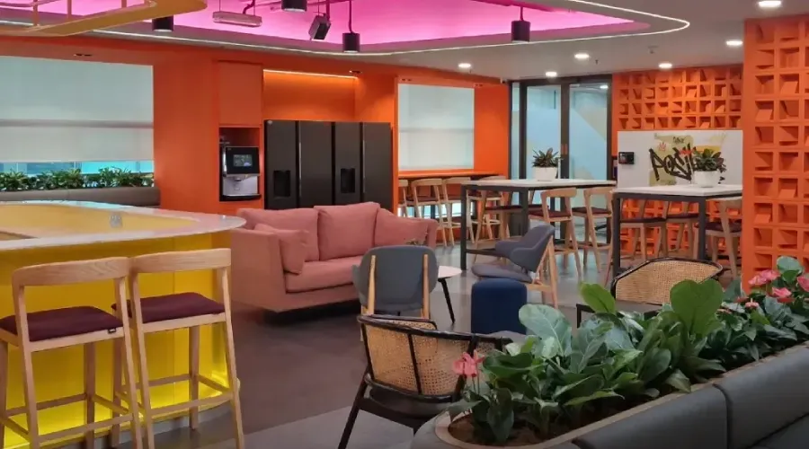 Modern TP office lounge with colorful seating, plants, and circular ceiling lights.