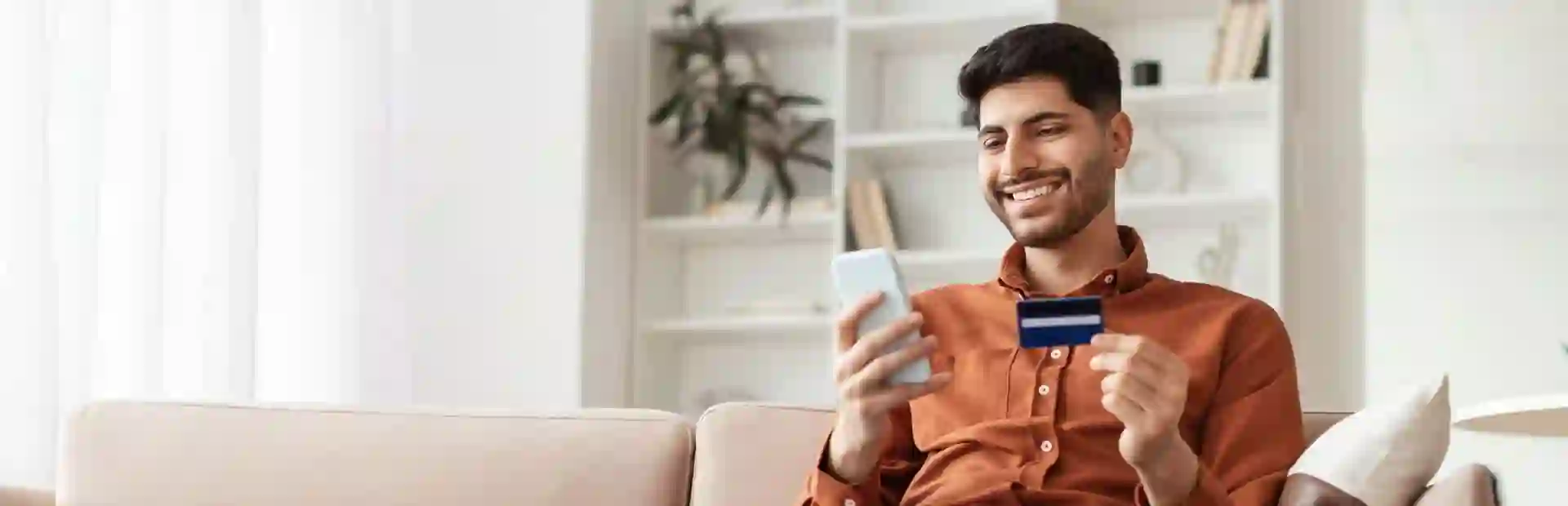 A man holding a credit card and smartphone, illustrating debt recovery services.