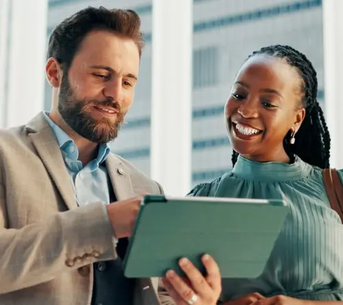 Smiling colleagues view a tablet in a modern office, evoking AI and emotional intelligence.