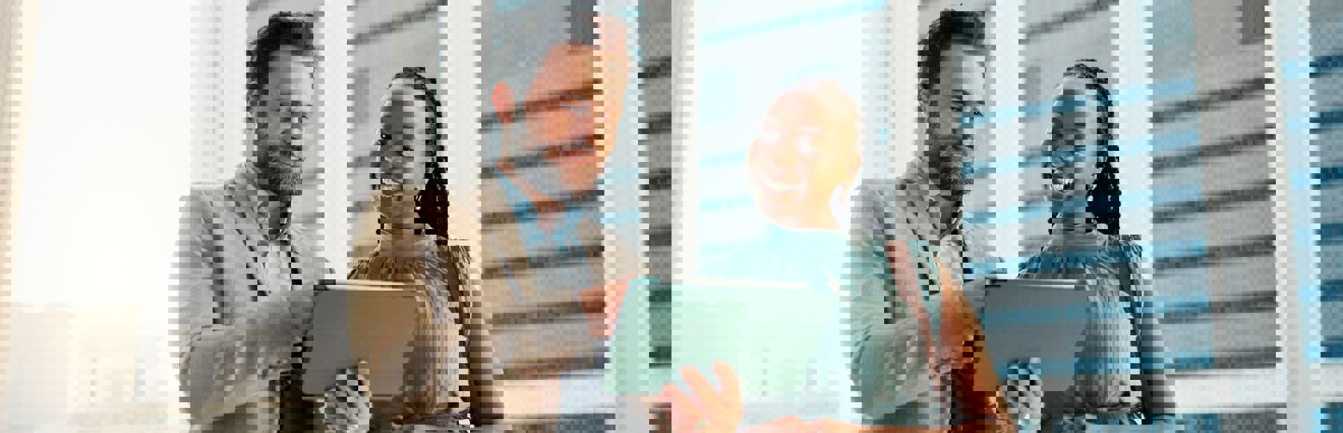 Smiling colleagues view a tablet in a modern office, evoking AI and emotional intelligence.