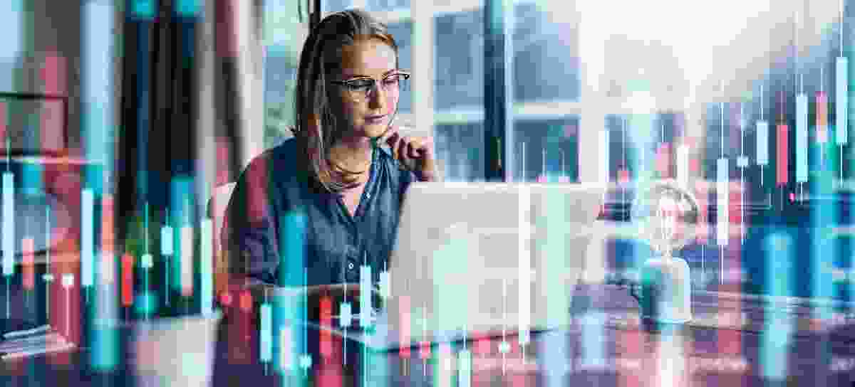 Focused business woman working on her laptop with 3D candlestick graph elements
