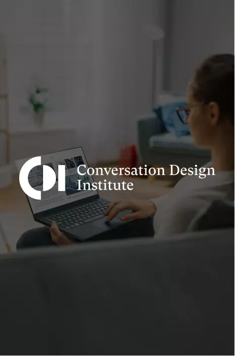Conversation Design Institute logo in focus with a woman browsing a laptop on the background