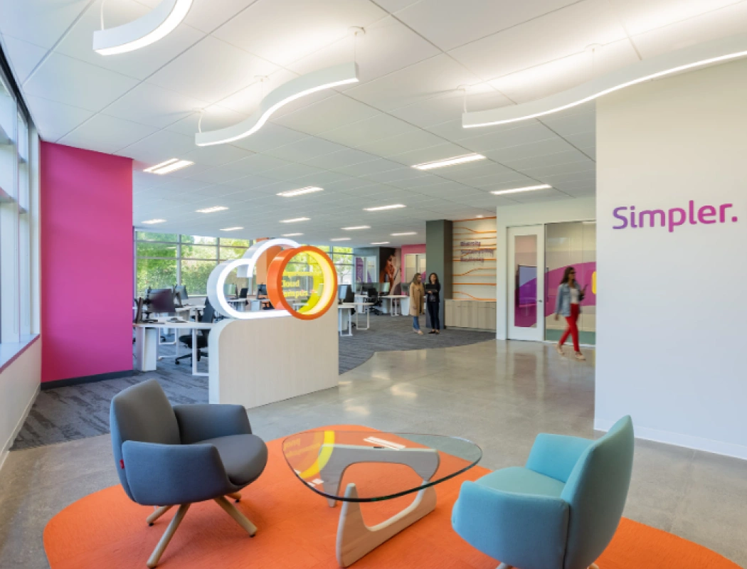A bright, open-plan modern office with colorful accents and collaborative spaces.