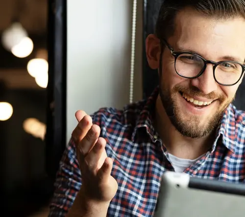 A man smiling while looking at a tablet
