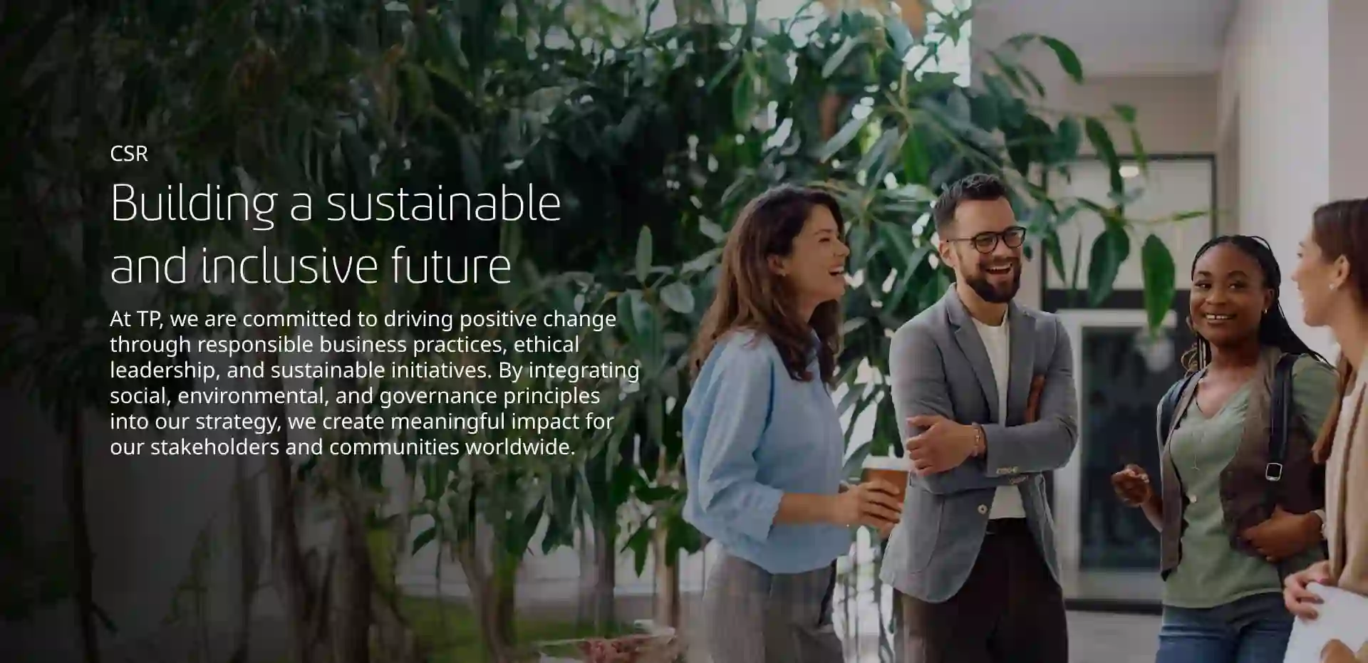 Group of employees talking and laughing in a modern, tree-lined office