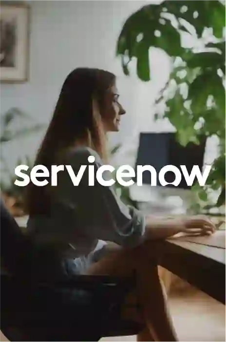 Service now logo in focus and a woman working on laptop 