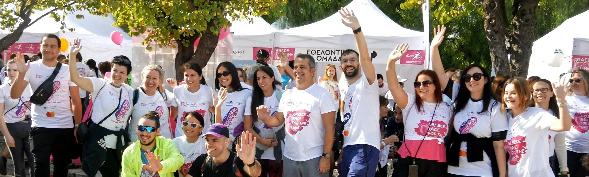 Group of volunteers smiling and waving at a community charity event.