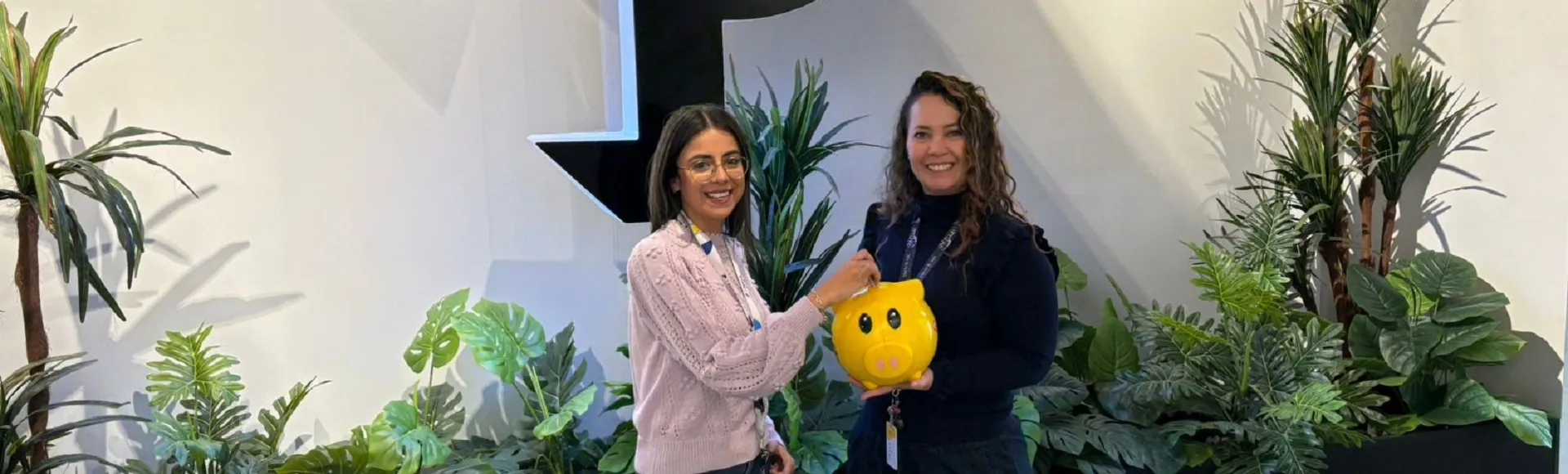 Two TP colleagues in Mexico hold a piggy bank symbolizing the TP and Teleton partnership.