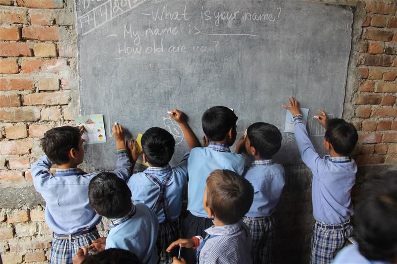 Group of schoolchildren in uniform writing on a blackboard.