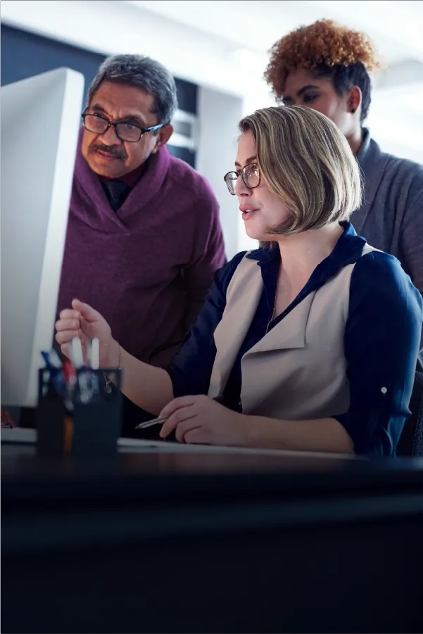 Team reviewing information together on a desktop computer in an office setting.