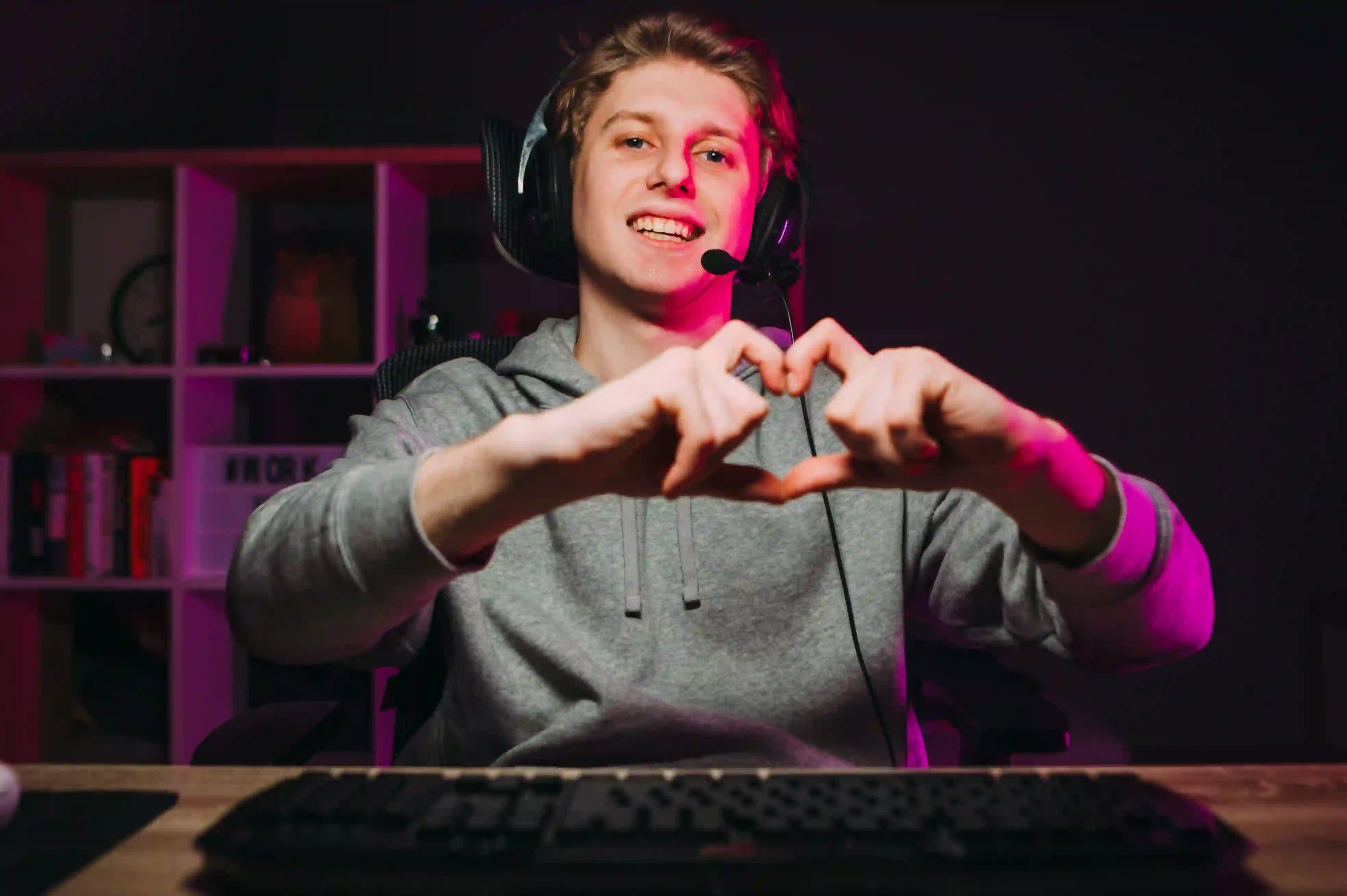 TP Russia employee working from home, wearing a headset and making a heart gesture with his hands in front of his computer.