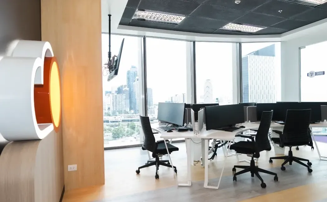 A bright, modern office interior featuring floor-to-ceiling windows offering a stunning panoramic view of the city skyline.