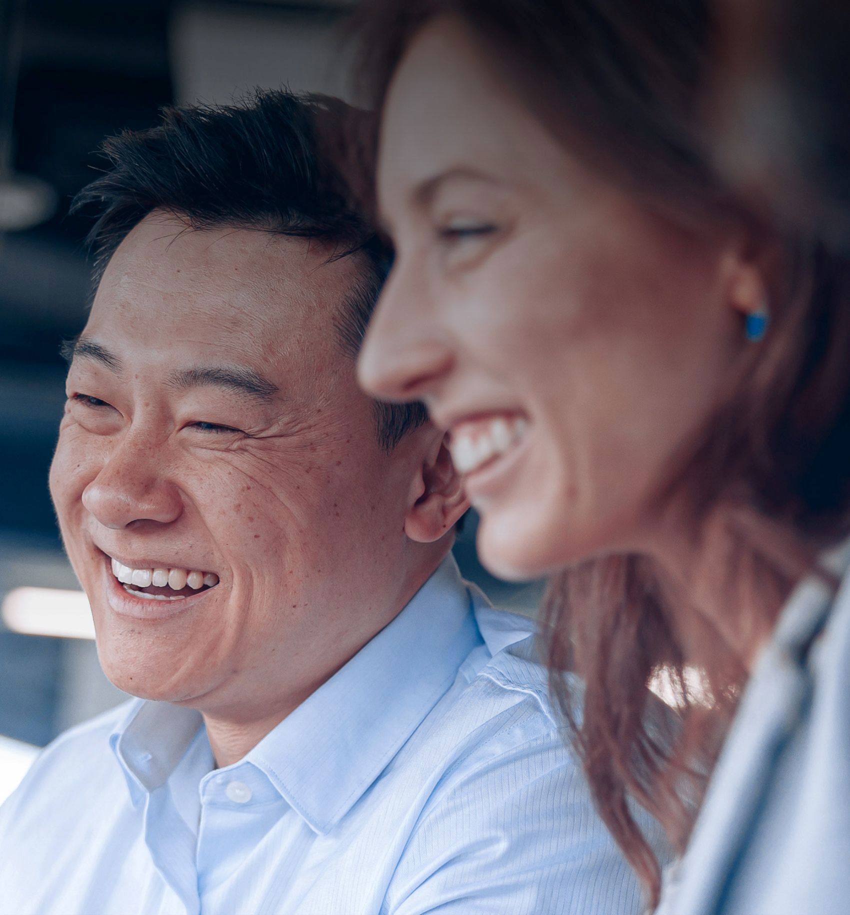 A diverse team of professionals laughs joyfully together in a bright modern office