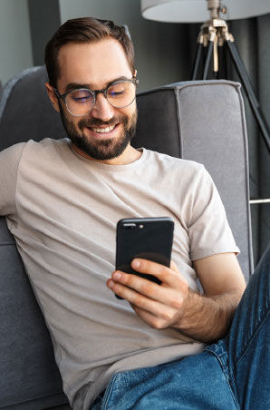 Smiling man sit relaxed while browsing his cellphone
