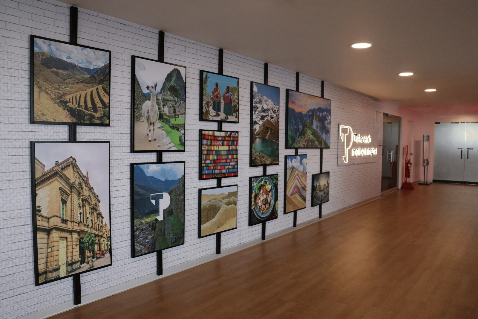 White bick wall with photo frames and a TP neon sign.