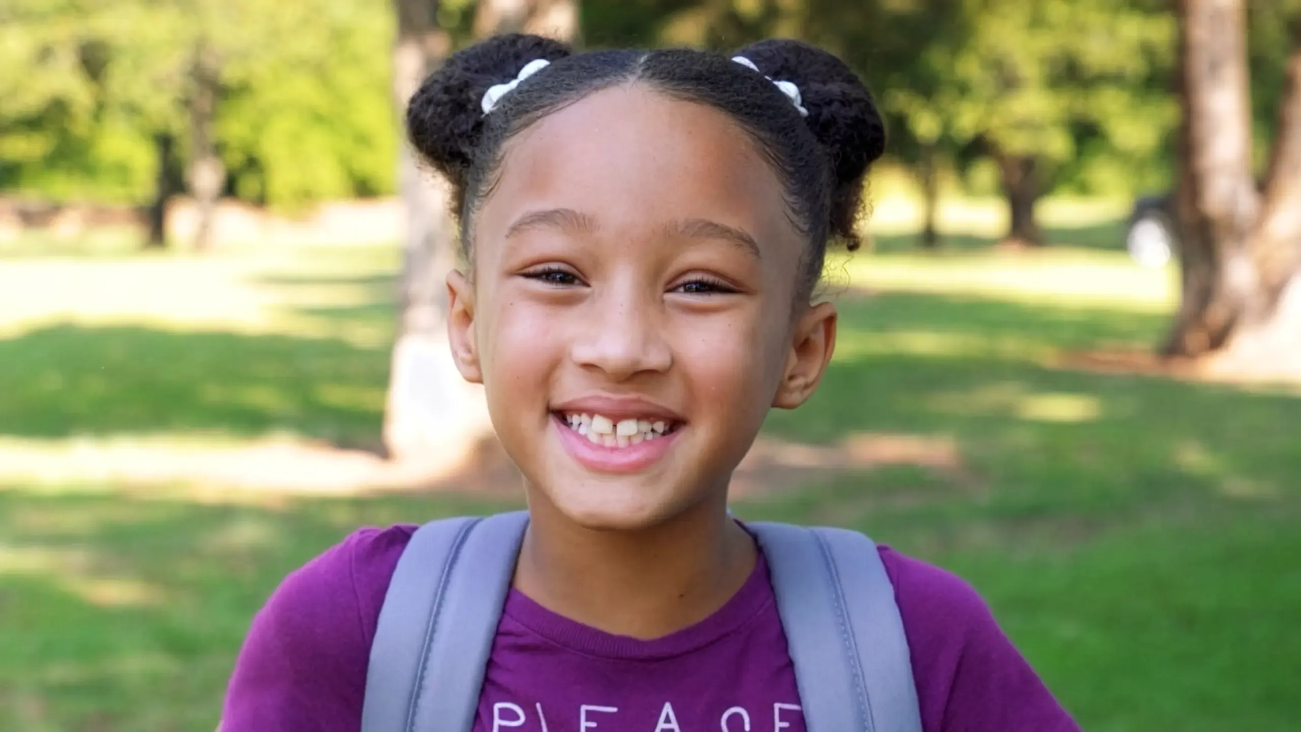 Smiling child with a backpack supported by a TP community education initiative.