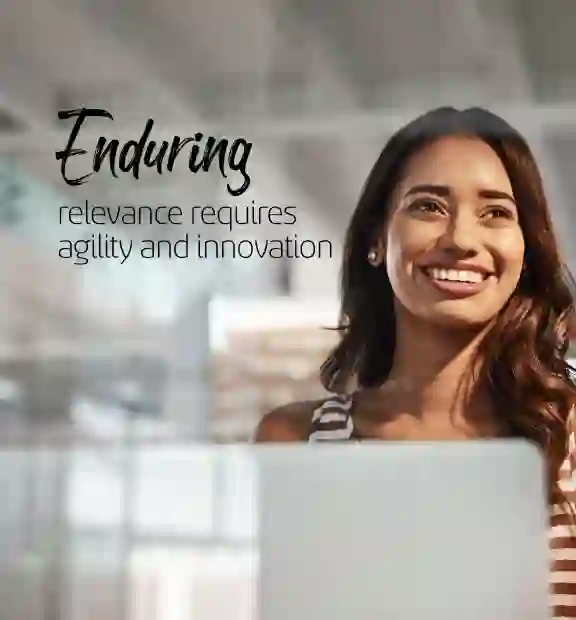 Smiling woman working on her laptop on a modern glass wall office