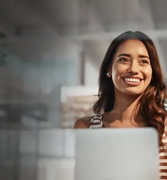 Smiling woman working on her laptop on a modern glass wall office