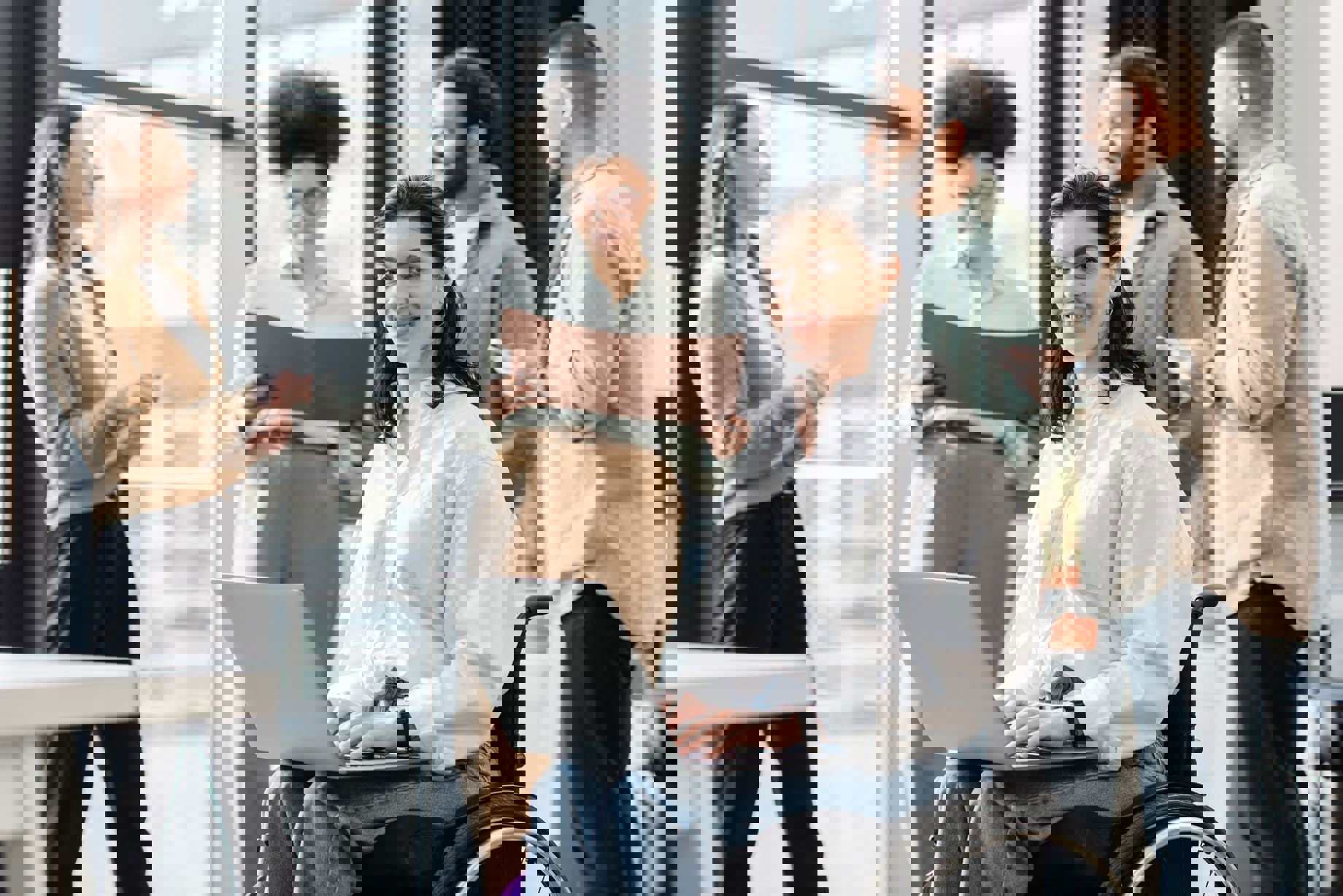 Wheelchair worker holding laptop and smiling at the camera