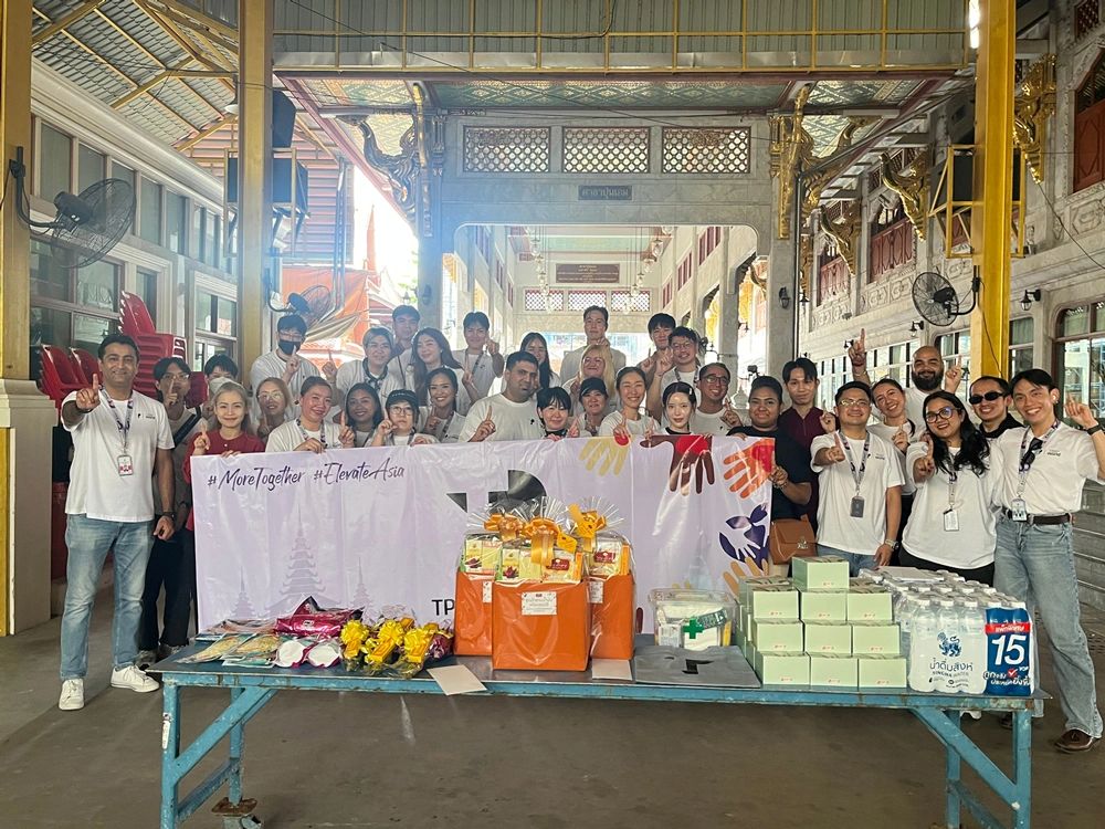 A diverse team of colleagues gathers proudly, showcasing donations and support for a charitable cause during a community outreach event