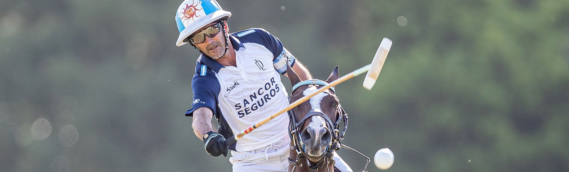 TP polo player in action, hitting the ball while riding at full speed during a match.