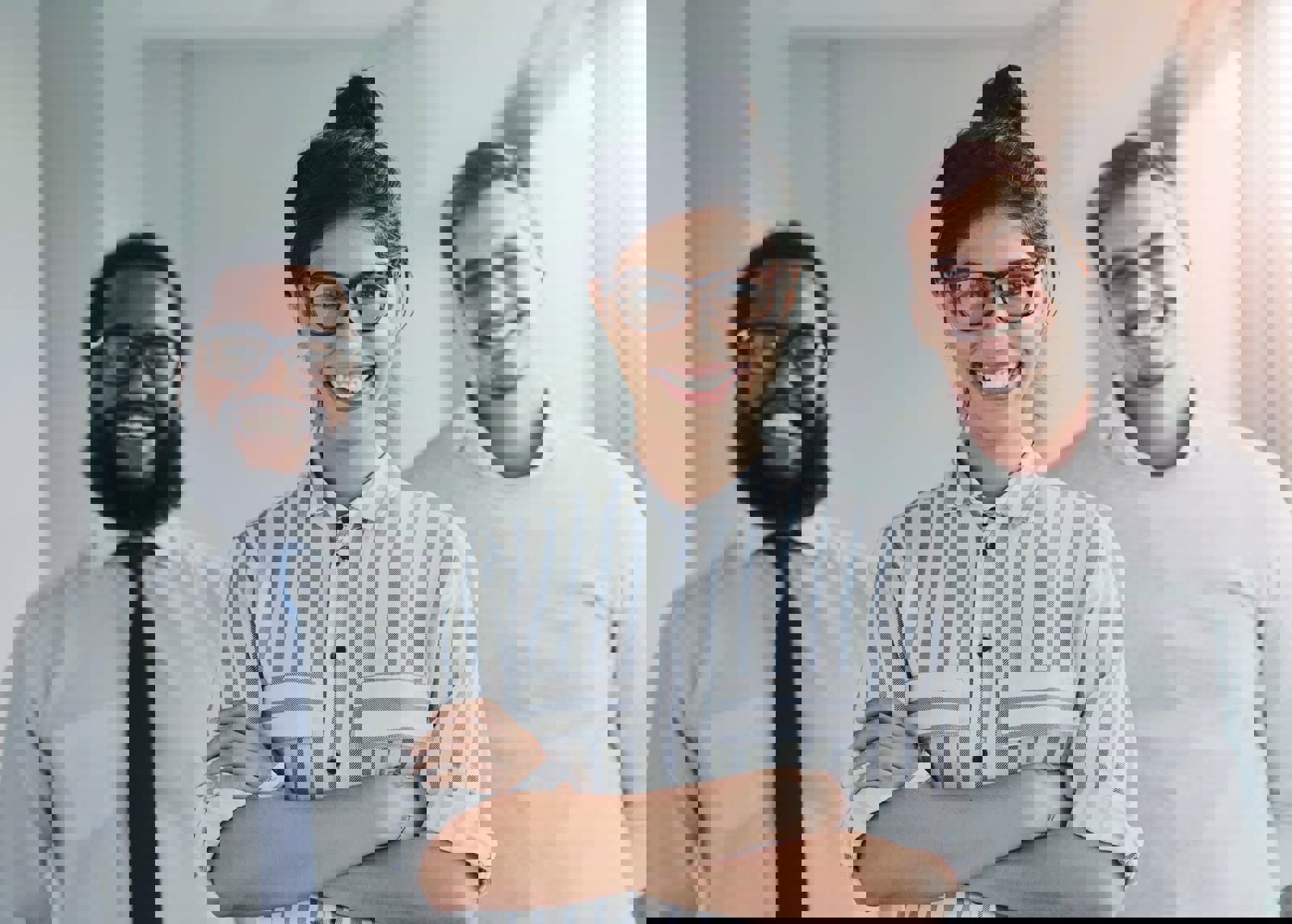 Three smiling professionals standing together indoors, dressed in business casual attire.