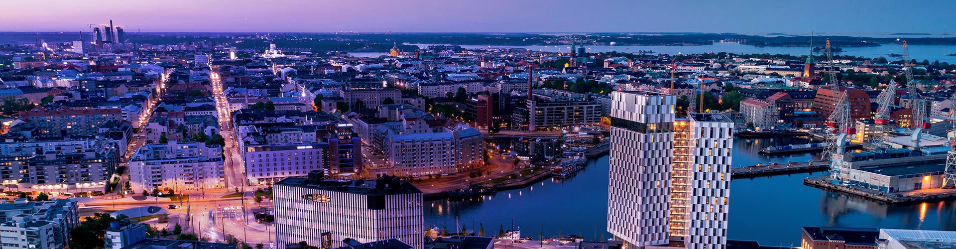 Helsinki cityscape at dusk with illuminated streets and waterfront buildings.
