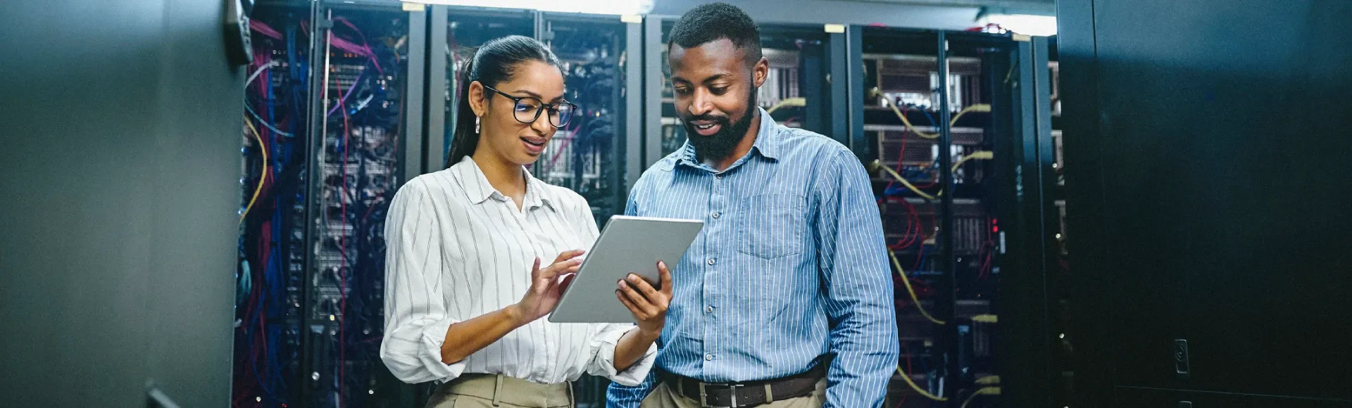 Two professionals working together inside a data center.