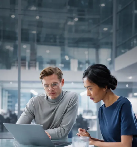 Two professionals reviewing data on a laptop in a modern office.