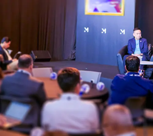 A business panel discussion with speakers on stage and an engaged audience.