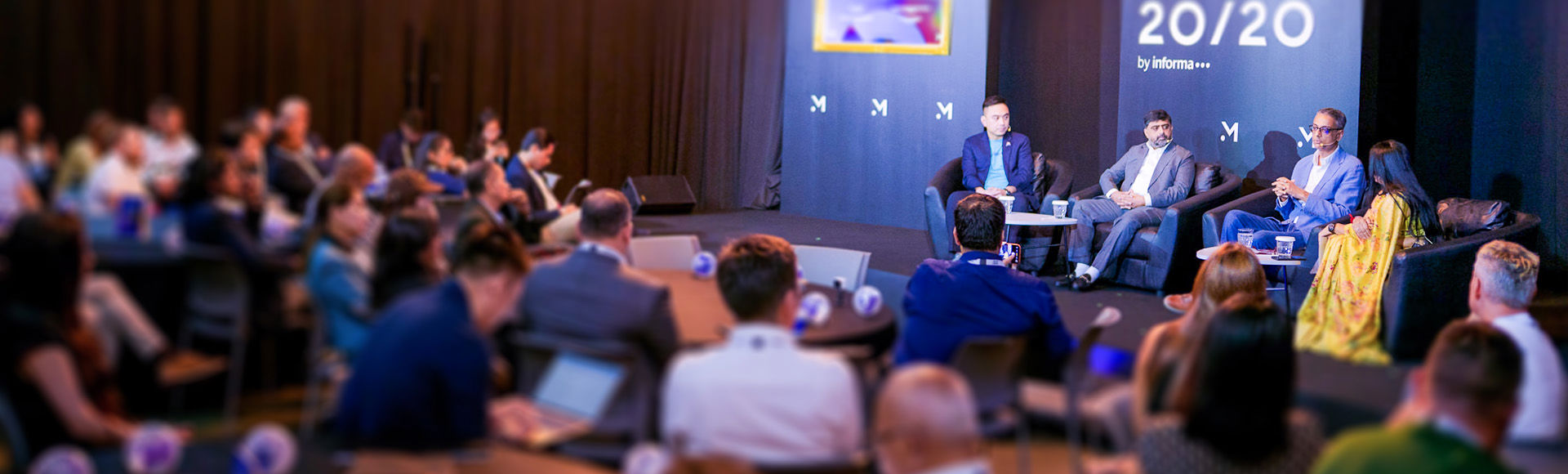 A business panel discussion with speakers on stage and an engaged audience.