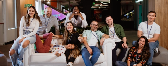 Team members posing together and smiling in a modern office lounge area.