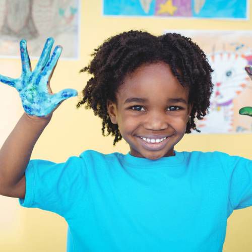 Smiling African kid shows his painted hands