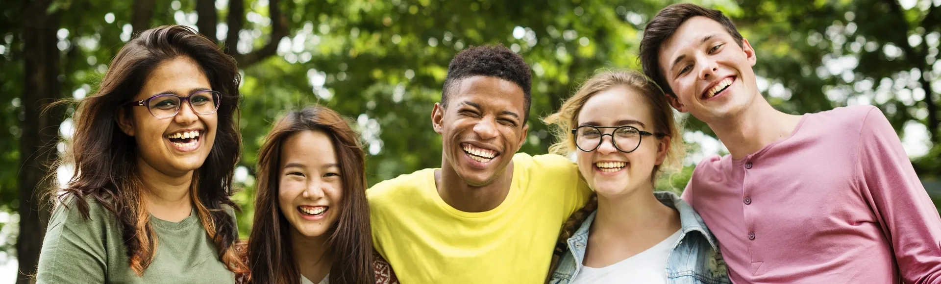 Group of diverse young adults smiling together outdoors.