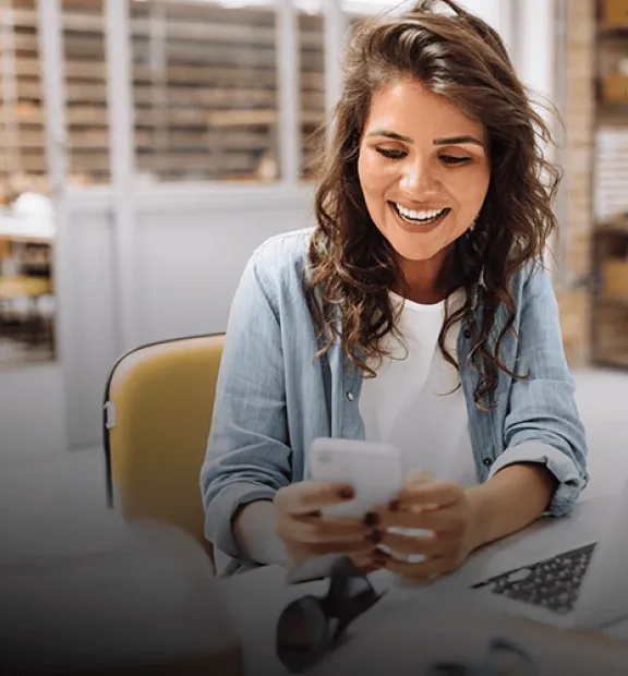 Woman smiling while looking at her phone at the office