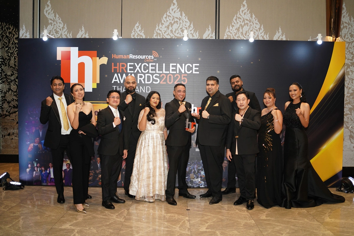 A diverse team in formal attire celebrates triumphantly at the HR Awards 2025 Thailand, proudly posing with their award