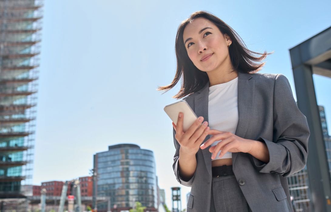 ChatGPT said:  Asian businesswoman on a modern street with her phone, reflecting agility through cloud-based solutions.